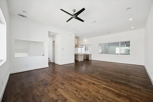 a view of empty room with wooden floor and ceiling fan