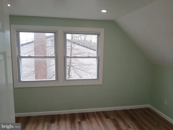 a view of an empty room with wooden floor and closet