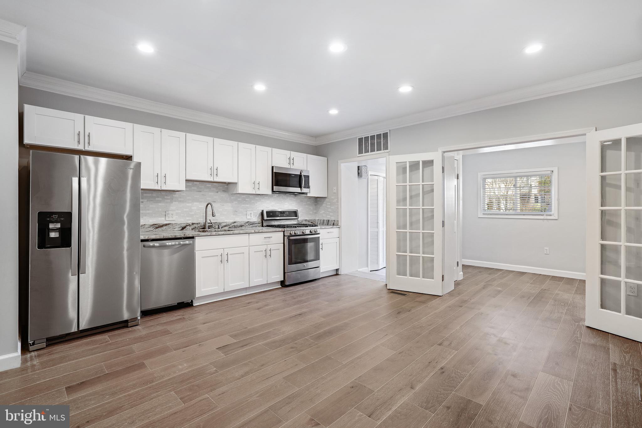a kitchen with wooden floors white cabinets and stainless steel appliances