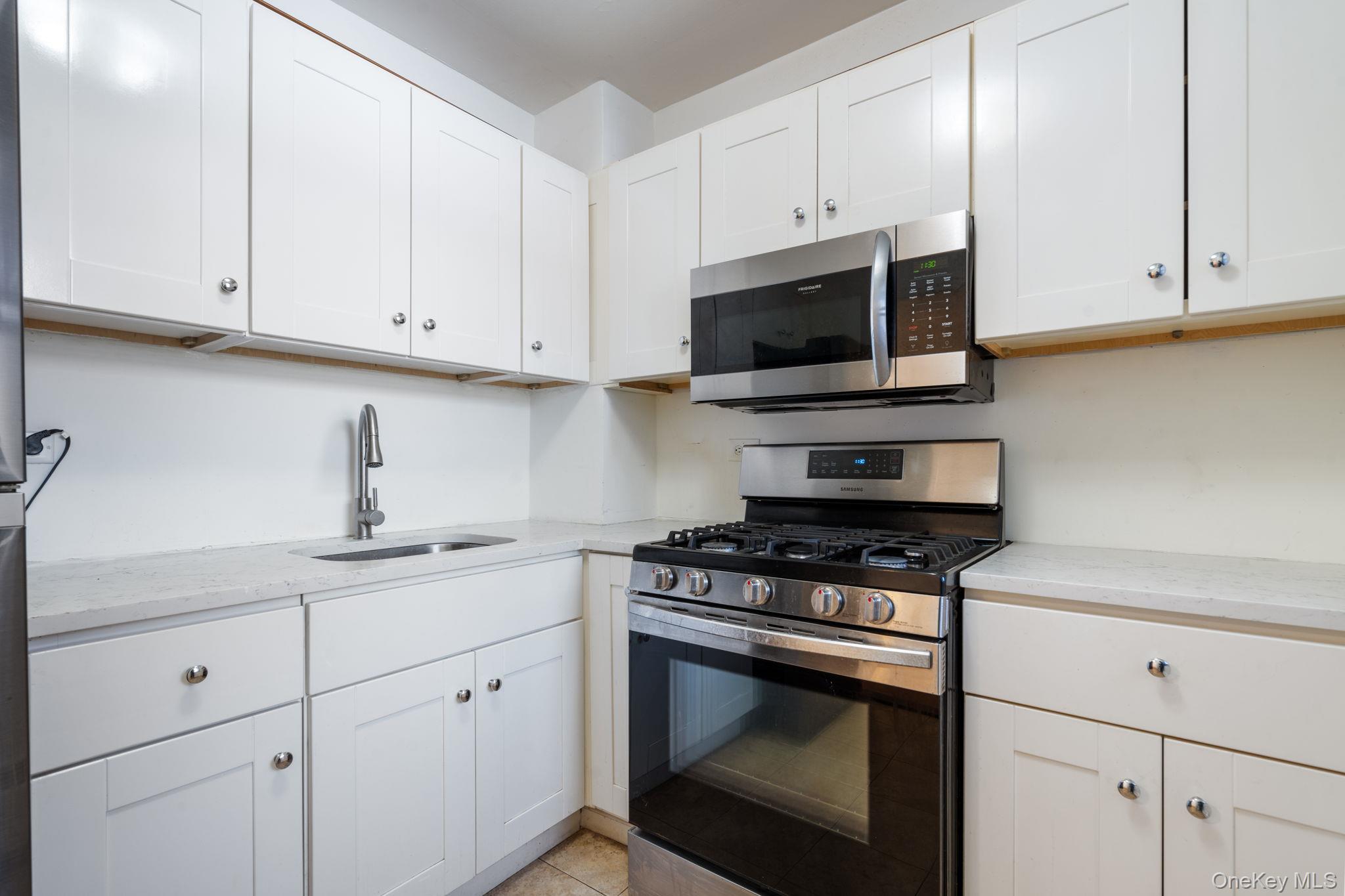 61-15 97th Street, Unit 2D Queens, NY 11374 - Photo 3 of 11 a kitchen with white cabinets and appliances