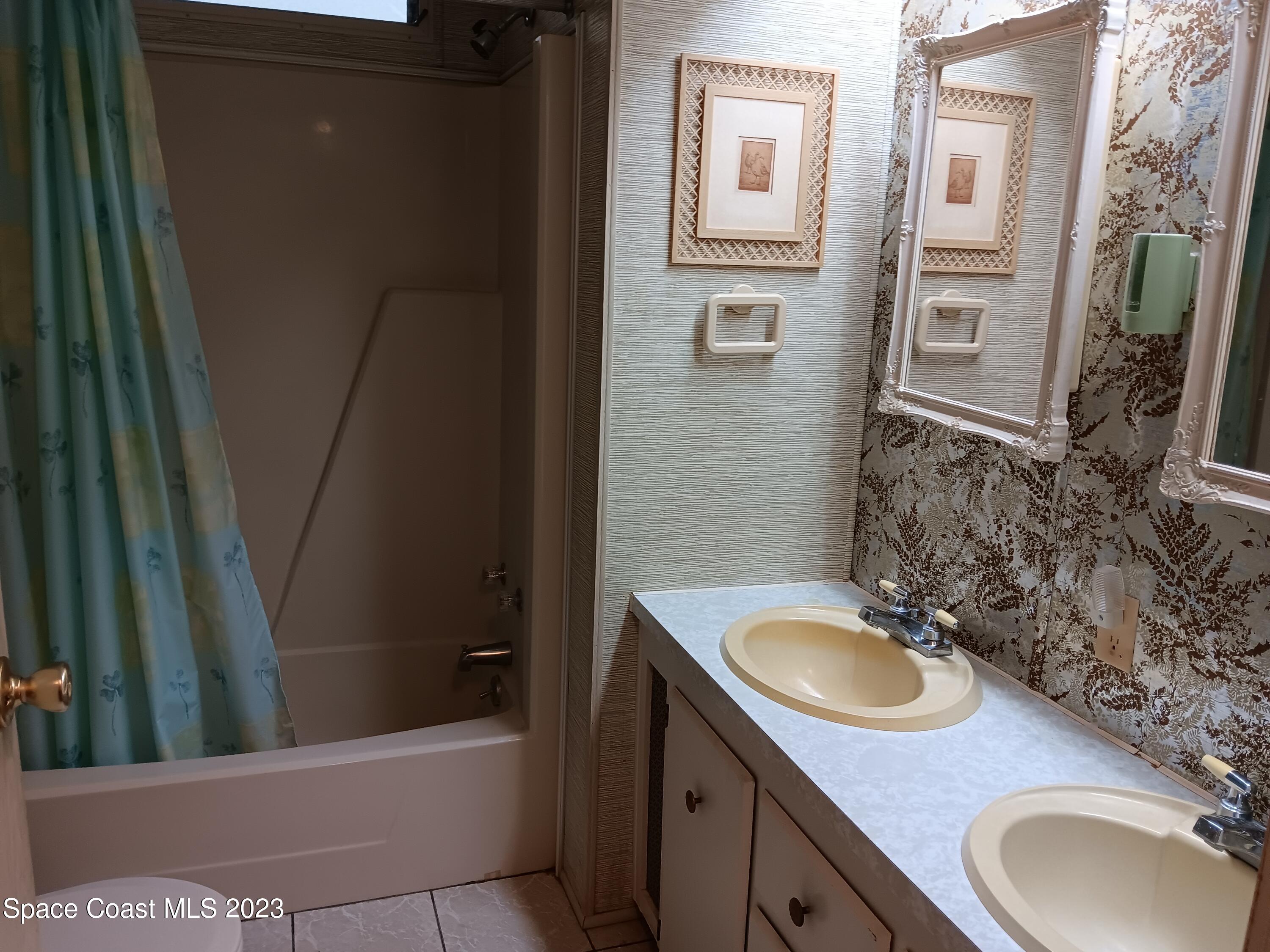 511 Puffin Drive Barefoot Bay, FL 32976 - Photo 24 of 25 a bathroom with a sink a toilet a mirror and vanity