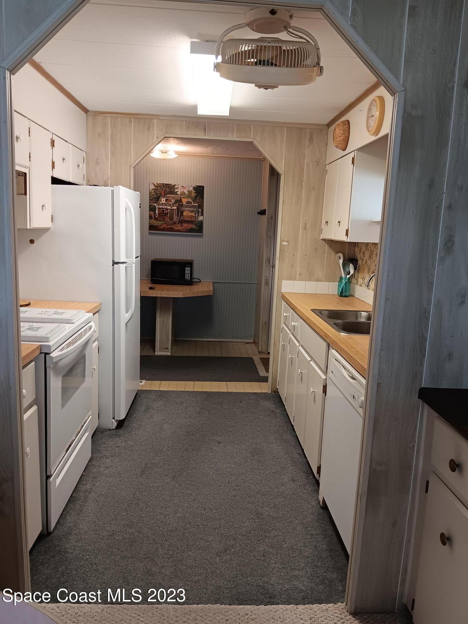 511 Puffin Drive Barefoot Bay, FL 32976 - Photo 10 of 25 a kitchen with white cabinets and stainless steel appliances
