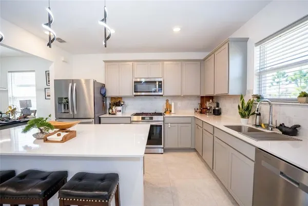 a kitchen with a refrigerator a stove a sink a dining table and chairs
