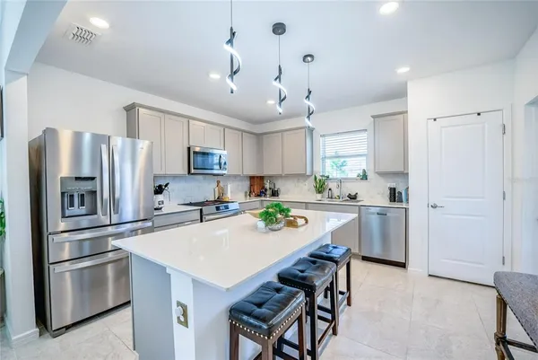 a kitchen with stainless steel appliances a refrigerator a stove a sink a dining table and chairs