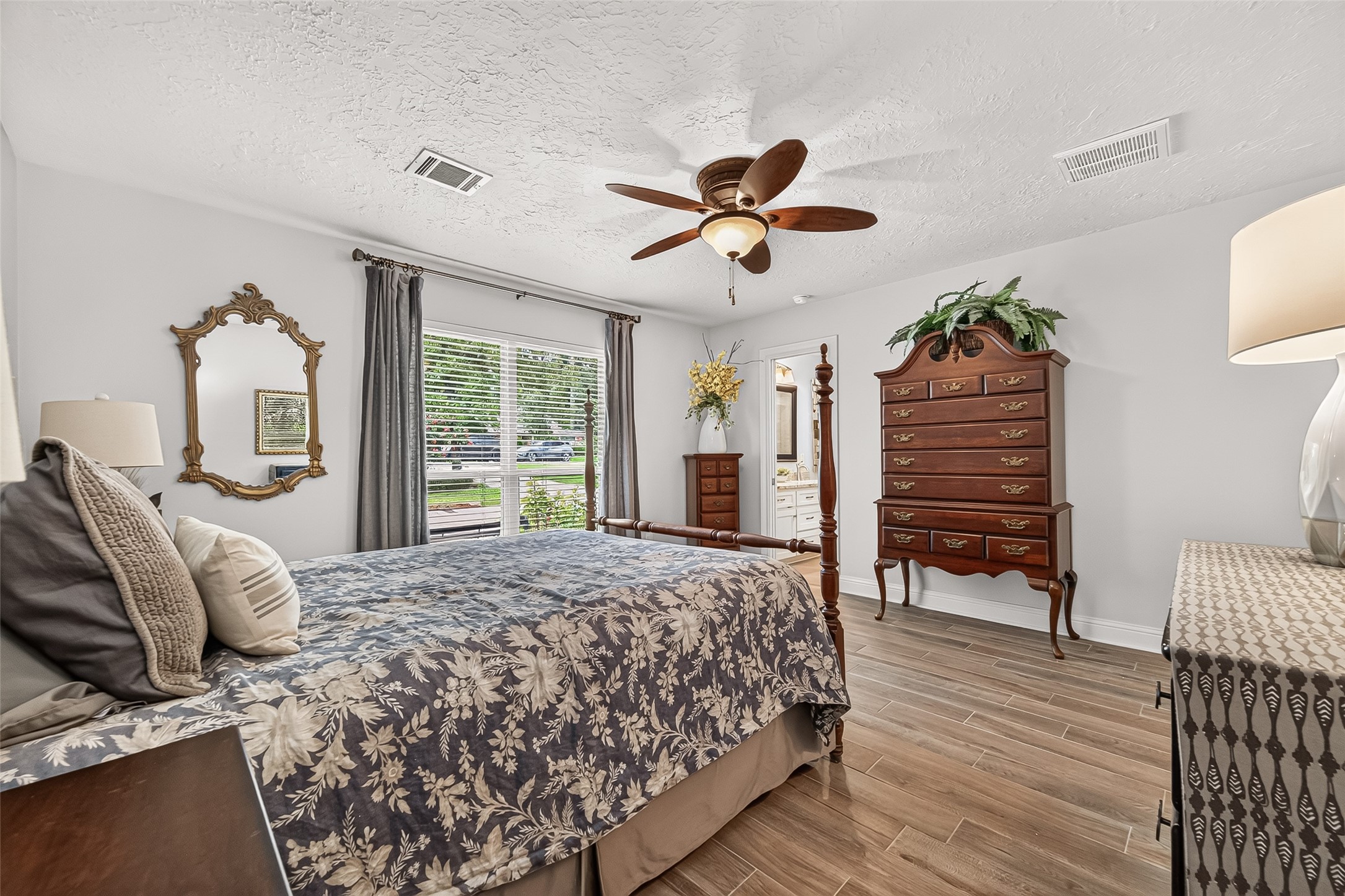 24719 Wilderness Road Spring, TX 77380 - Photo 26 of 42 This spacious primary bedroom features elegant ceramic tile flooring, a stylish ceiling fan, and ample natural light from large windows with blinds.