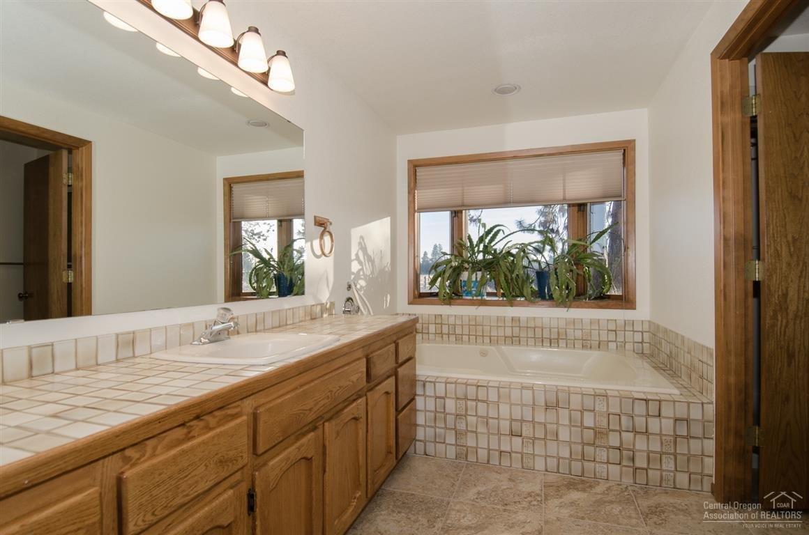 20903 Knott Road Bend, OR 97702 - Photo 20 of 23 a bathroom with a granite countertop sink a large mirror and a bathtub
