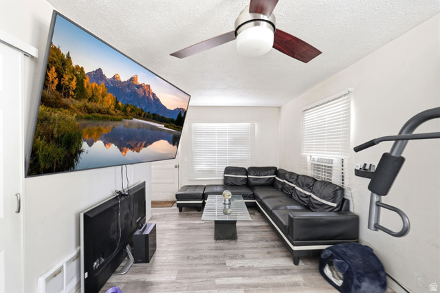 5480 South 2000th Street West Roy, UT 84067 - Photo 13 of 36 Living area featuring wood-finish flooring, white walls, and a ceiling fan with integrated lighting