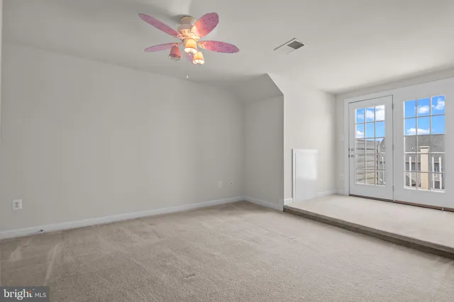 an empty room with chandelier fan and windows
