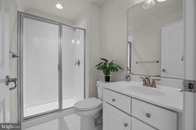 a bathroom with a sink a toilet a glass door a shower and a mirror