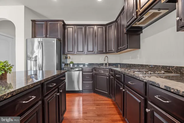 a kitchen with granite countertop a refrigerator stove and sink