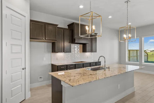a kitchen with kitchen island granite countertop a sink and refrigerator