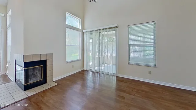 an empty room with wooden floor fireplace and windows