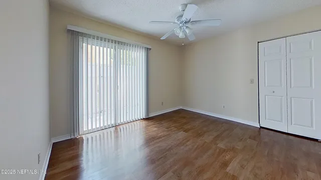 a view of an empty room with wooden floor and a window