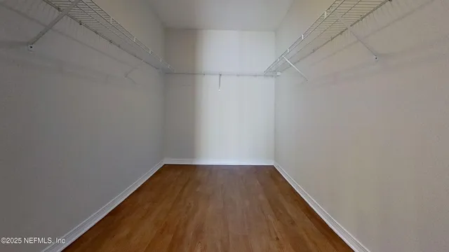 an empty room with wooden floor chandelier fan and windows