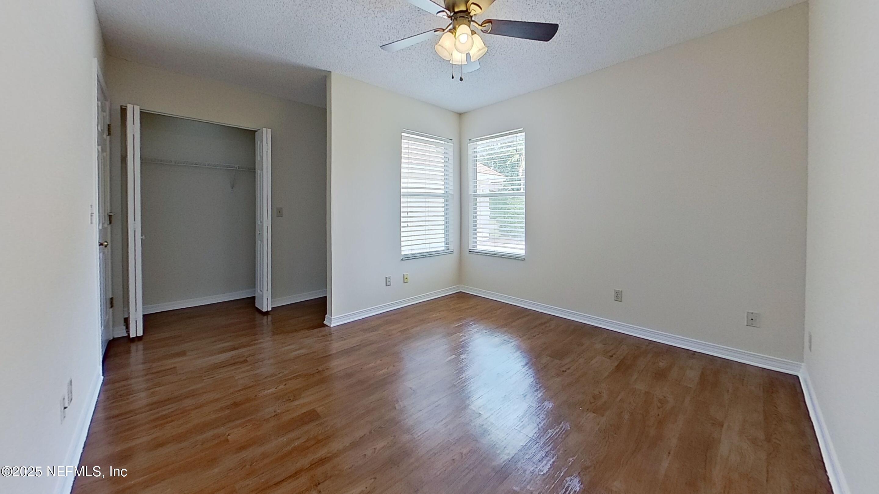1488 Marsh Rabbit Way Fleming Island, FL 32003 - Photo 26 of 35 an empty room with wooden floor chandelier fan and windows