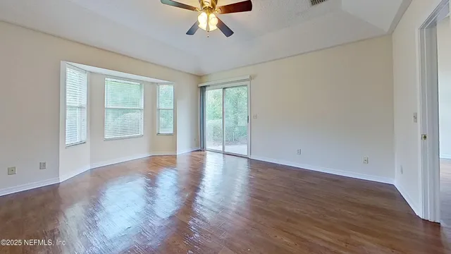 an empty room with wooden floor and windows