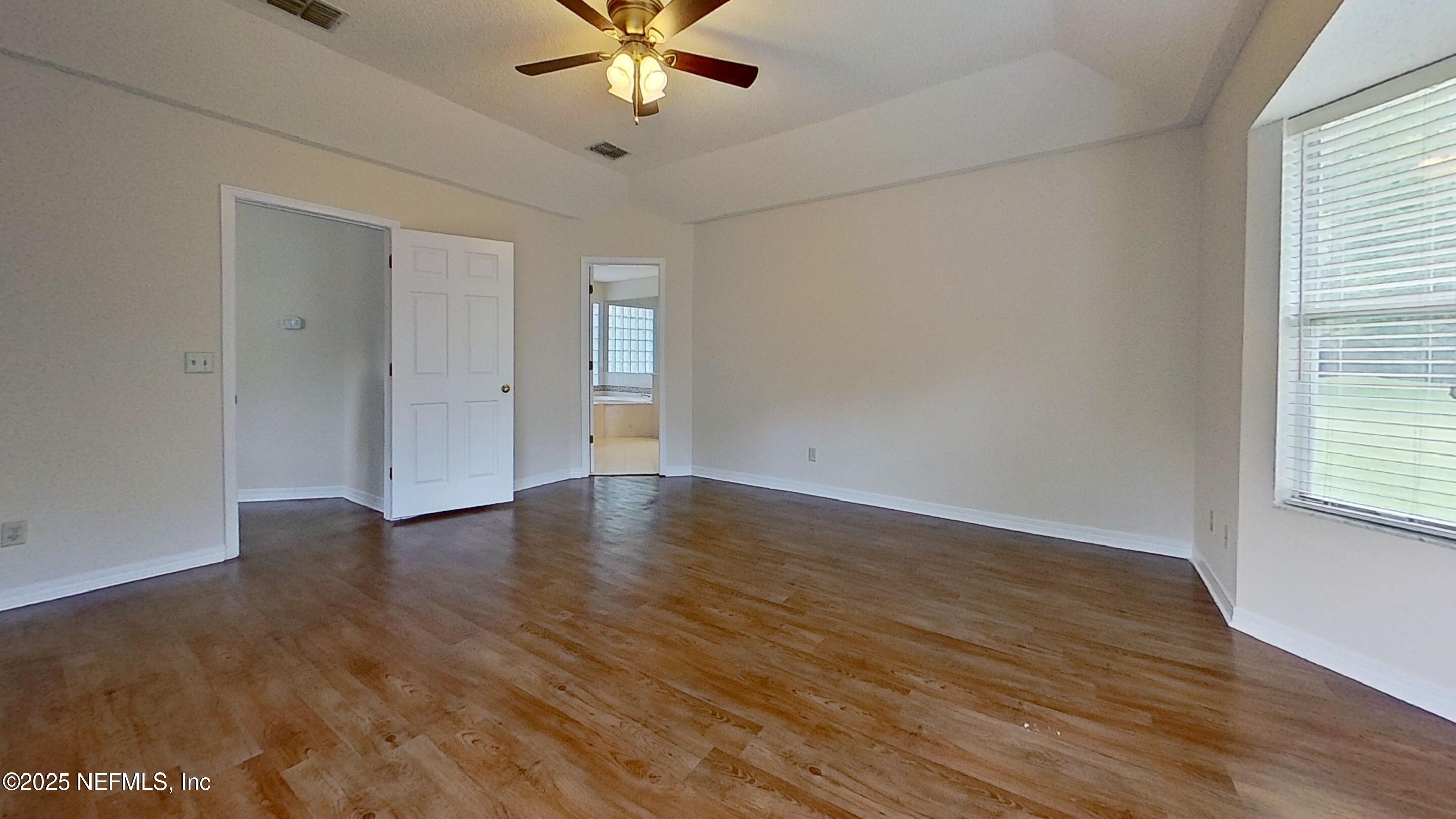 1488 Marsh Rabbit Way Fleming Island, FL 32003 - Photo 29 of 35 an empty room with wooden floor and windows