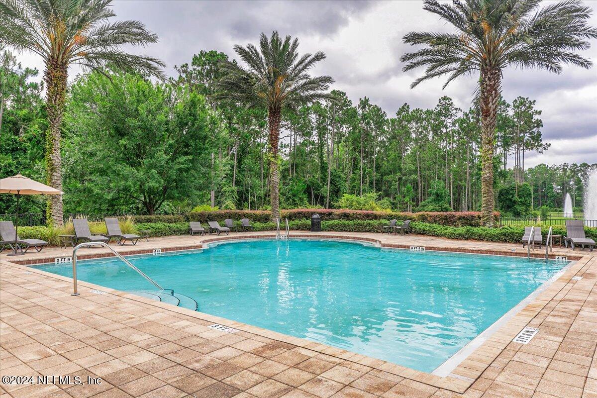 103 Spring Tide Way Ponte Vedra, FL 32081 - Photo 26 of 26 a view of a swimming pool with a lounge chair and palm trees