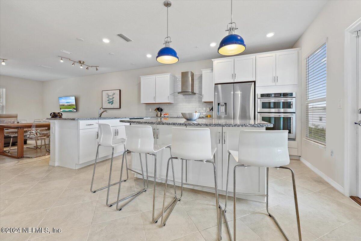 103 Spring Tide Way Ponte Vedra, FL 32081 - Photo 6 of 26 a kitchen with kitchen island granite countertop a table chairs refrigerator and microwave