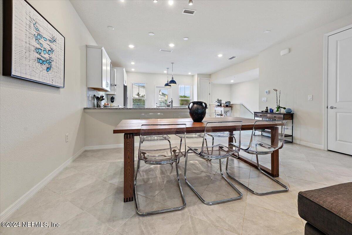 103 Spring Tide Way Ponte Vedra, FL 32081 - Photo 9 of 26 a kitchen with stainless steel appliances kitchen island granite countertop a dining table chairs sink and white cabinets