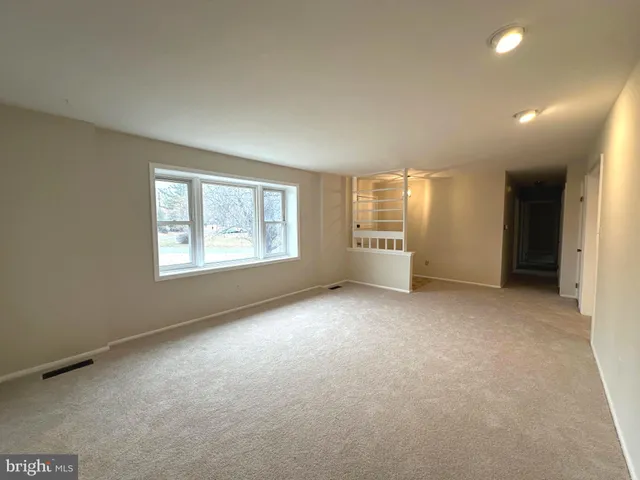 an empty room with windows and chandelier fan