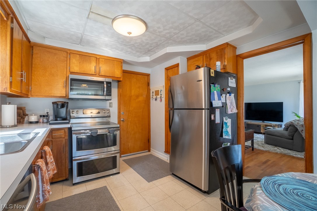 Kitchen featuring countertops light, washbasin, light tile flooring, and appliances with stainless steel finishes