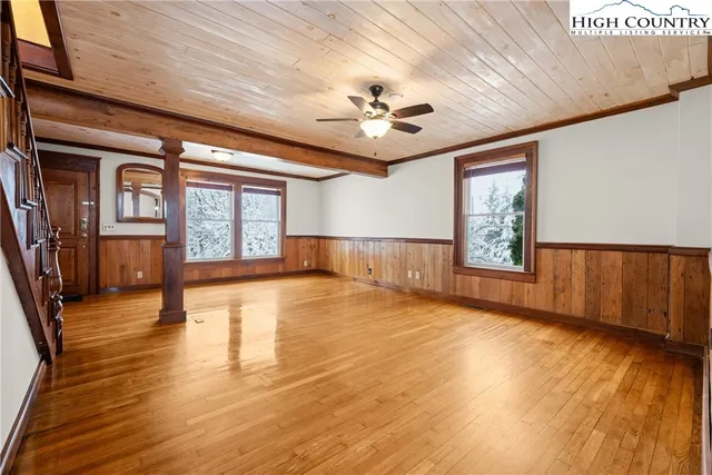 a view of an empty room with a window and wooden floor