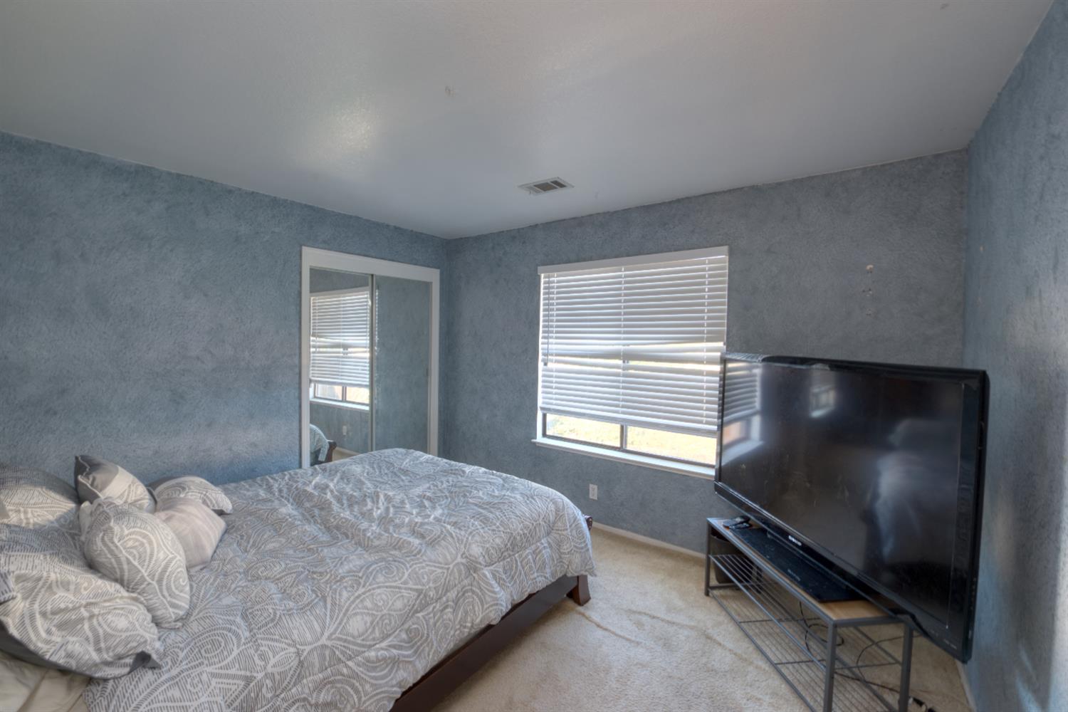 548 Hansen Court Patterson, CA 95363 - Photo 22 of 38 a bedroom with a bed television window and a flat screen tv