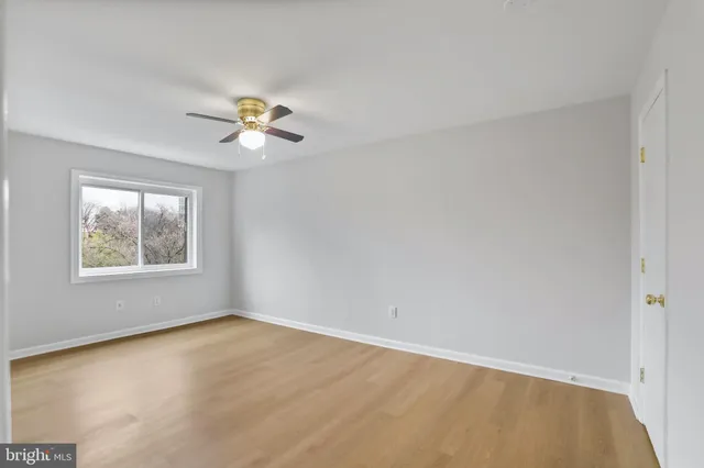 an empty room with a window and a ceiling fan
