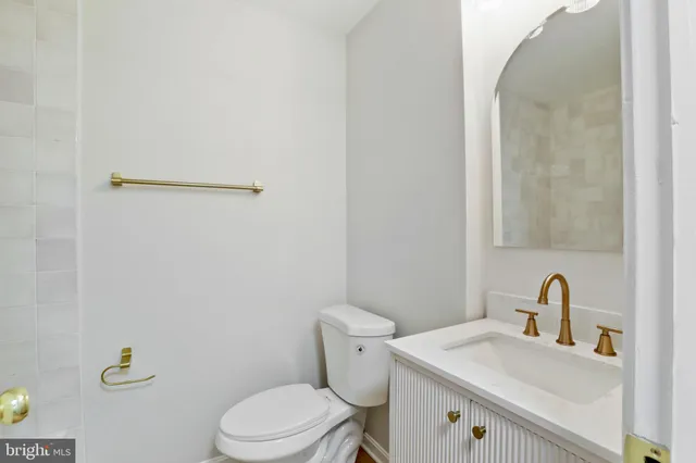 a bathroom with a toilet sink vanity and mirror