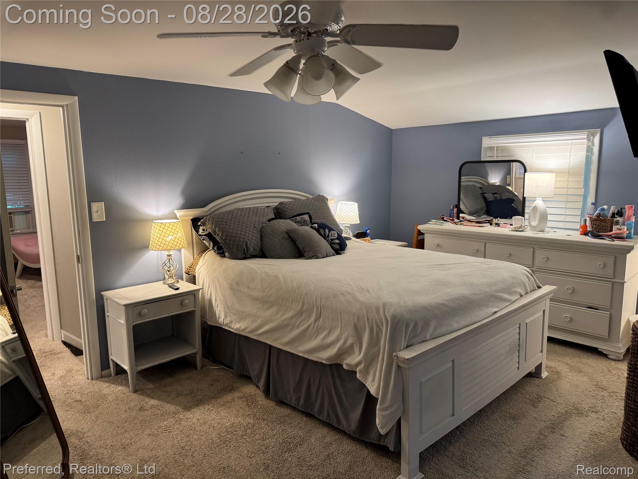 10362 Quirk Road Belleville, MI 48111 - Photo 32 of 41 Spacious primary bedroom featuring soft blue accent walls, ceiling fan with integrated lighting, wood-finish nightstand with built-in shelf storage, and coordinating wood-finish dresser with mirror