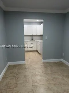 a view of a refrigerator in kitchen and an empty room