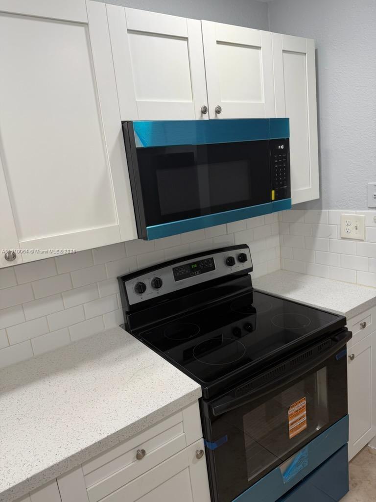 1805 West 56th Street, Unit 412 Hialeah, FL 33012 - Photo 6 of 18 a close view of a stove a microwave and cabinets in a kitchen