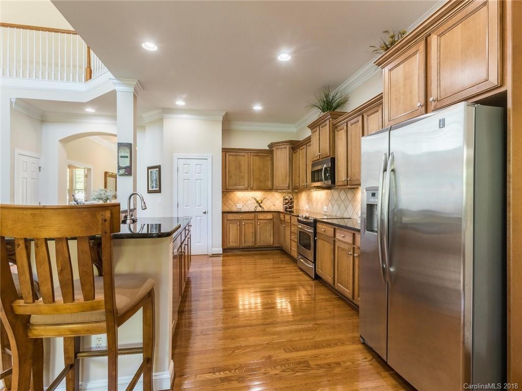 3325 Richard's Crossing Fort Mill, SC 29708 - Photo 14 of 36 a kitchen with stainless steel appliances granite countertop a refrigerator a oven a sink and a dining table with wooden floor