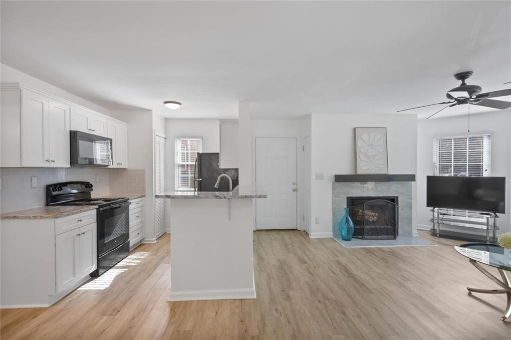 102 Hawkstone Way Alpharetta, GA 30022 - Photo 6 of 22 a kitchen with granite countertop a stove top oven a sink dishwasher and a fireplace with wooden floor
