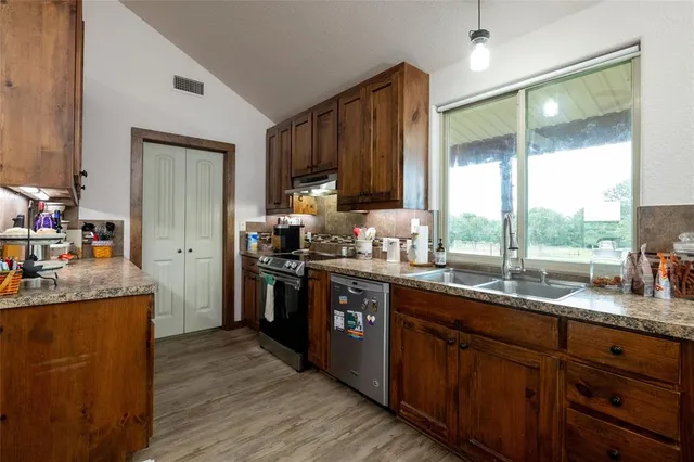 a kitchen with stainless steel appliances granite countertop a sink a stove and a refrigerator