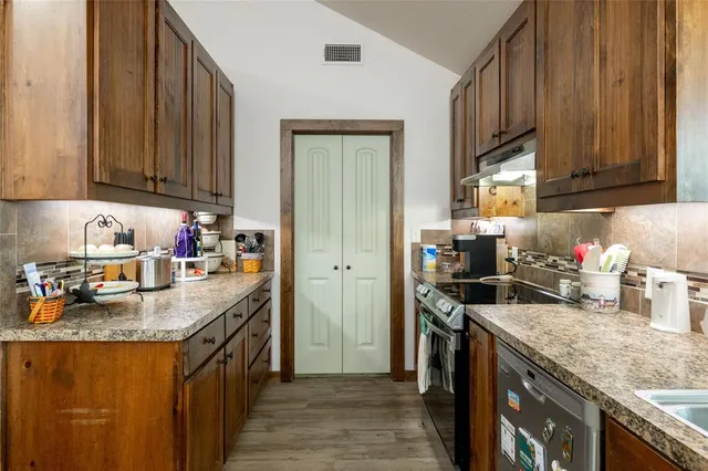 a kitchen with granite countertop a sink stove and cabinets