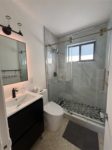 a bathroom with a sink a toilet a mirror and shower