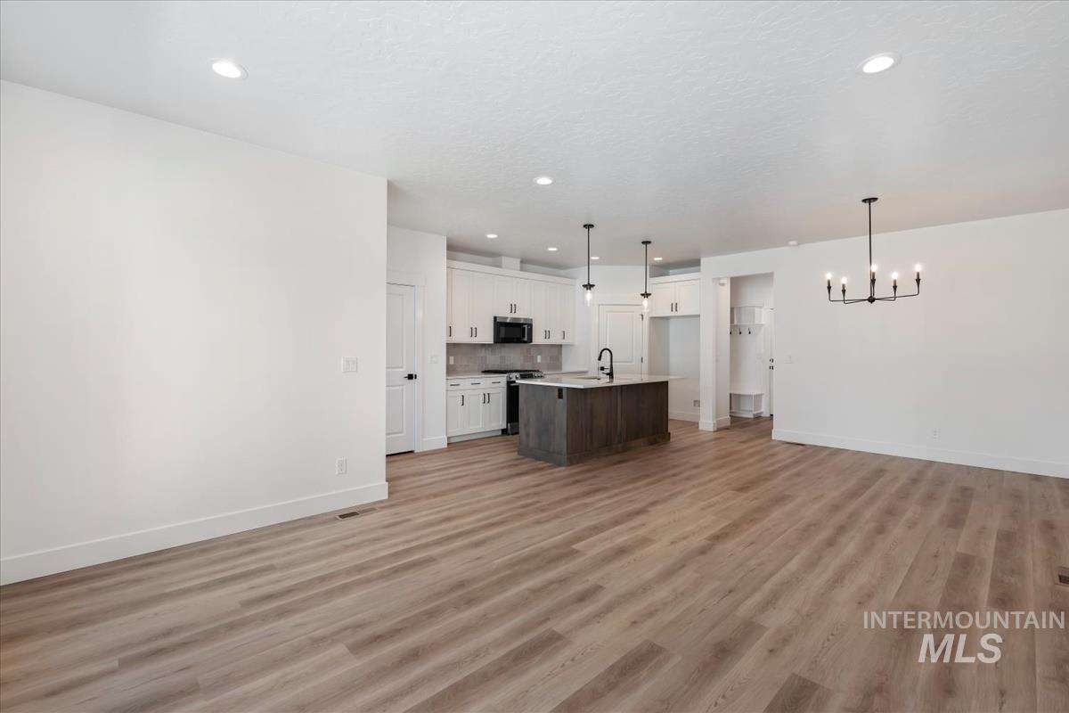 768 South Calhoun Lane Star, ID 83669 - Photo 3 of 36 Spacious interior with wood-finish flooring, recessed lighting, and a modern kitchen featuring an island with a dark wood-finish base and pendant lights