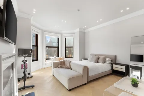 a spacious bedroom with a bed window table and television