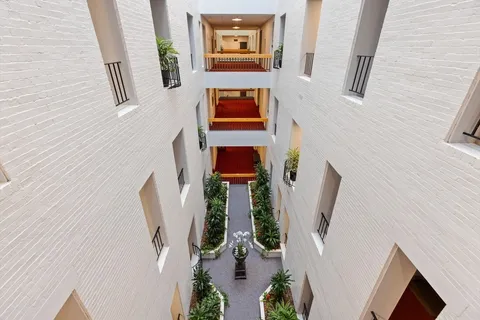 a room with a black white checkered floor with couches and glass table