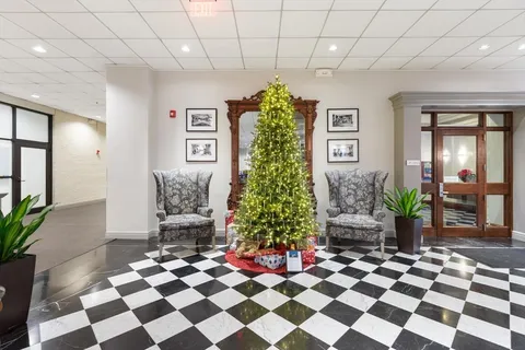 a front view of a building with lot of cars and trees