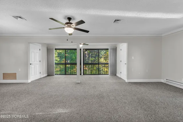 a view of an empty room with window and ceiling fan