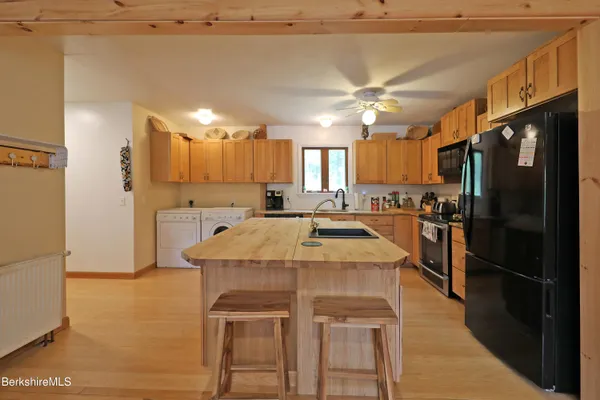 a kitchen with kitchen island a stove a refrigerator and a oven with wooden floor