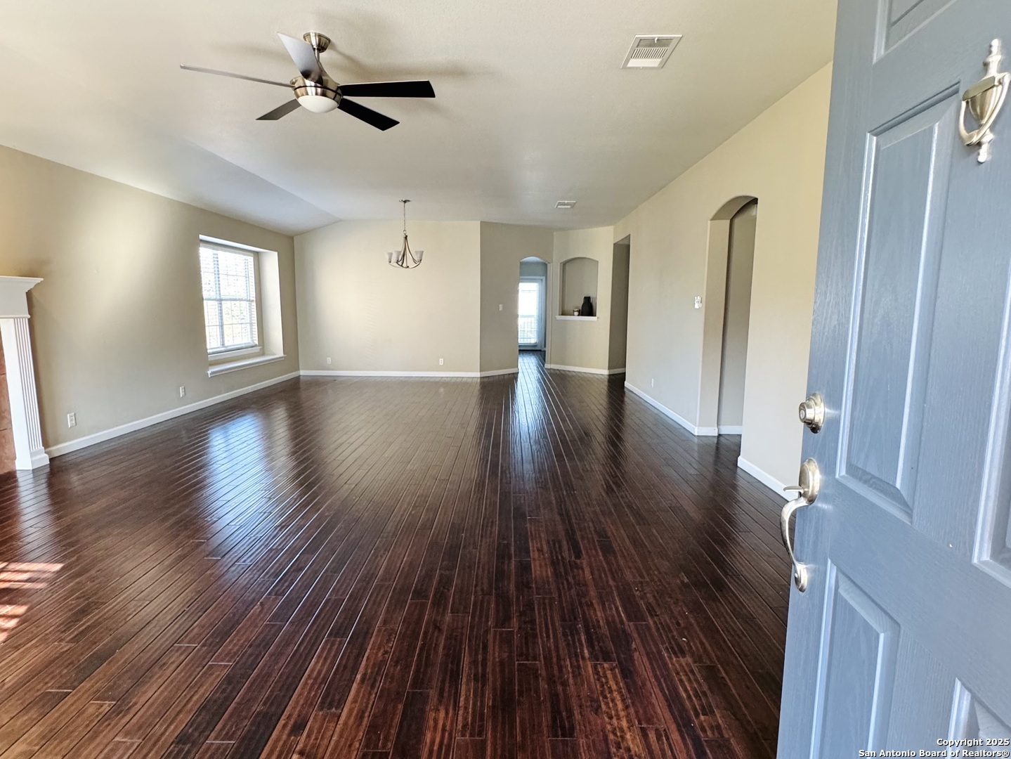 a view of empty room with wooden floor and fan