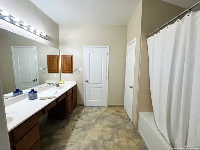 a bathroom with a double vanity sink a mirror and a bathtub