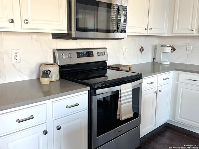 a kitchen with granite countertop white cabinets and white appliances