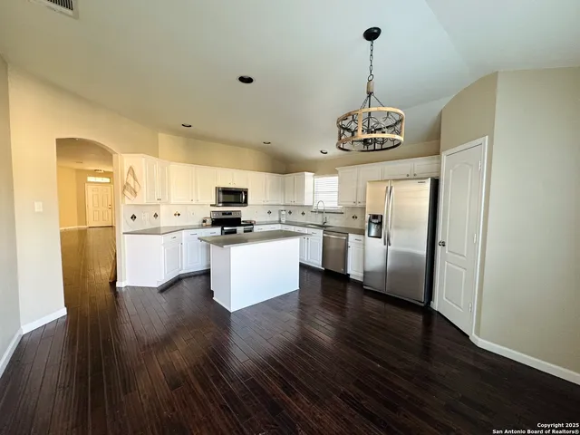a view of a kitchen with stainless steel appliances granite countertop a stove top oven a refrigerator a sink dishwasher with a dining table and chairs