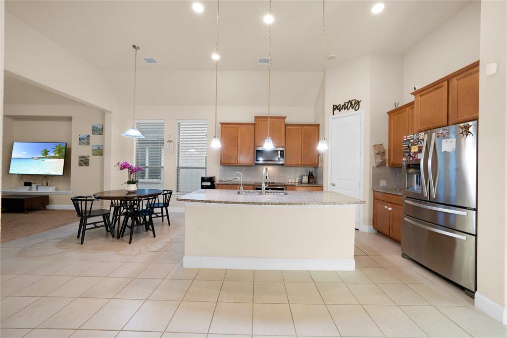 7024 Green Field Street Little Elm, TX 76227 - Photo 3 of 27 a large kitchen with kitchen island a dining table and chairs