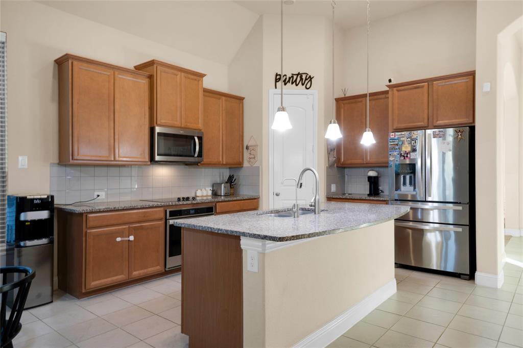 7024 Green Field Street Little Elm, TX 76227 - Photo 4 of 27 a kitchen with stainless steel appliances granite countertop a refrigerator a stove a sink and a microwave